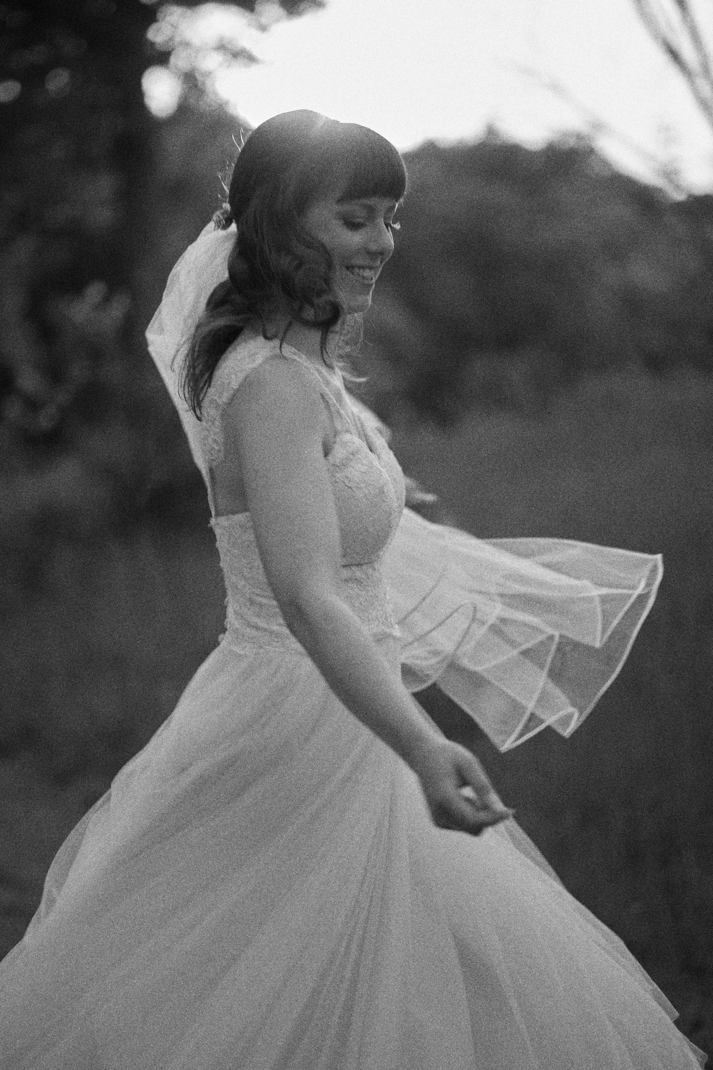 A bride turns in her gown, photographed in black and white